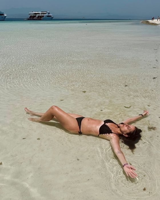 Vanessa Cesarano distesa a braccia aperte nell’acqua bassa di una spiaggia.
