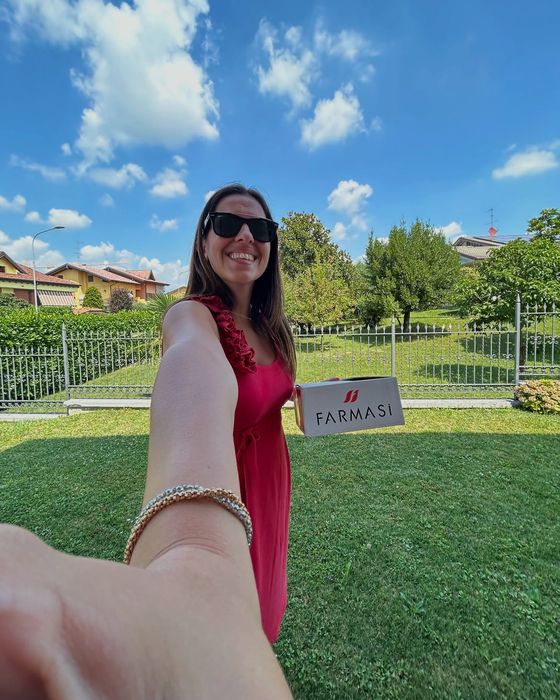 Vanessa Cesarano sorride in giardino con una scatola Farmasi sotto il braccio.